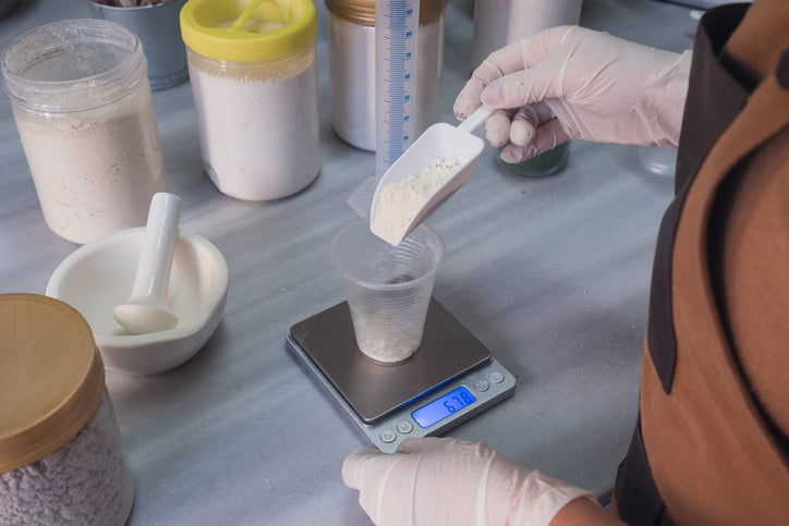 Hand measuring supplement powder on a precision scale